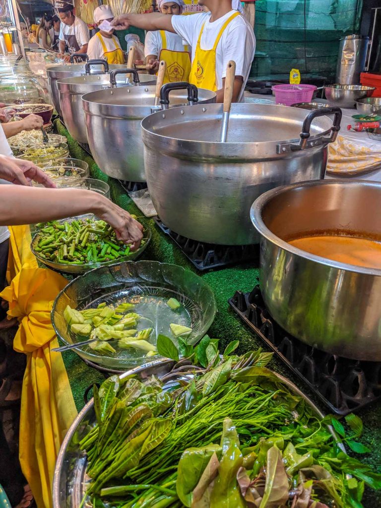 View of items offered by a kanom jeen (curry noodles) vendor, with pots of curry and condiments.